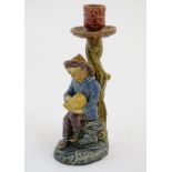 A continental candlestick decorated with a fisherman boy holding a nautilus shell.