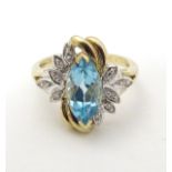 A 9ct gold ring set with central marquise cut topaz flanked by diamonds.