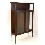Arts & Crafts - A late 19thC / early 20thC walnut glazed cabinet with gallery above and raised on