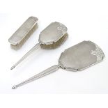 A three piece silver dressing table set comprising 2 brushes and a hand mirror all with engine