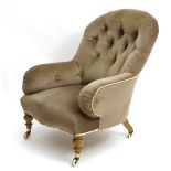 A Victorian armchair with button back upholstery and arm rests and standing on turned legs