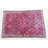 Carpet / rug : a hand woven woollen rug with red central ground and 78 diamond shaped decorations
