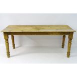 A late 19thC / early 20thC pine kitchen table standing on turned tapering legs.