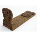 A large South Asian carved wooden extending book slide with hinged ends with floral and foliate