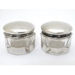 A pair of glass pots with silver tops hallmarked Birmingham 1918 maker G & C Ltd.