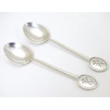 A pair of silver teaspoons marked RNLI to handles and with crossed golf club detail.