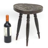 A 19thC circular three legged stool with carved seat top, unusually depicting tad poles,
