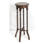 An early 20thC oak jardiniere stand with barley twist supports and across stretcher.