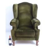 A 20thC green upholstered wingback armchair, raised on cabriole front legs and squared back legs.