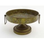 Arts and Crafts : a brass over copper tazza / comport with embossed decoration and drop handles,
