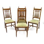 A set of four oak Arts and Crafts dining chairs with finial terminals, slatted back rests,