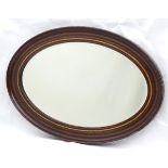 A mid 20thC oval bevelled mirror with crossbanded detailing to the frame.