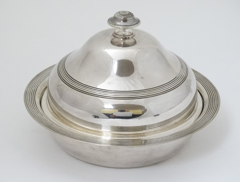 A silver plate muffin dish and cover .