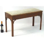 An early 20thC mahogany window seat / duet stool with upholstered seat and lifting lid,