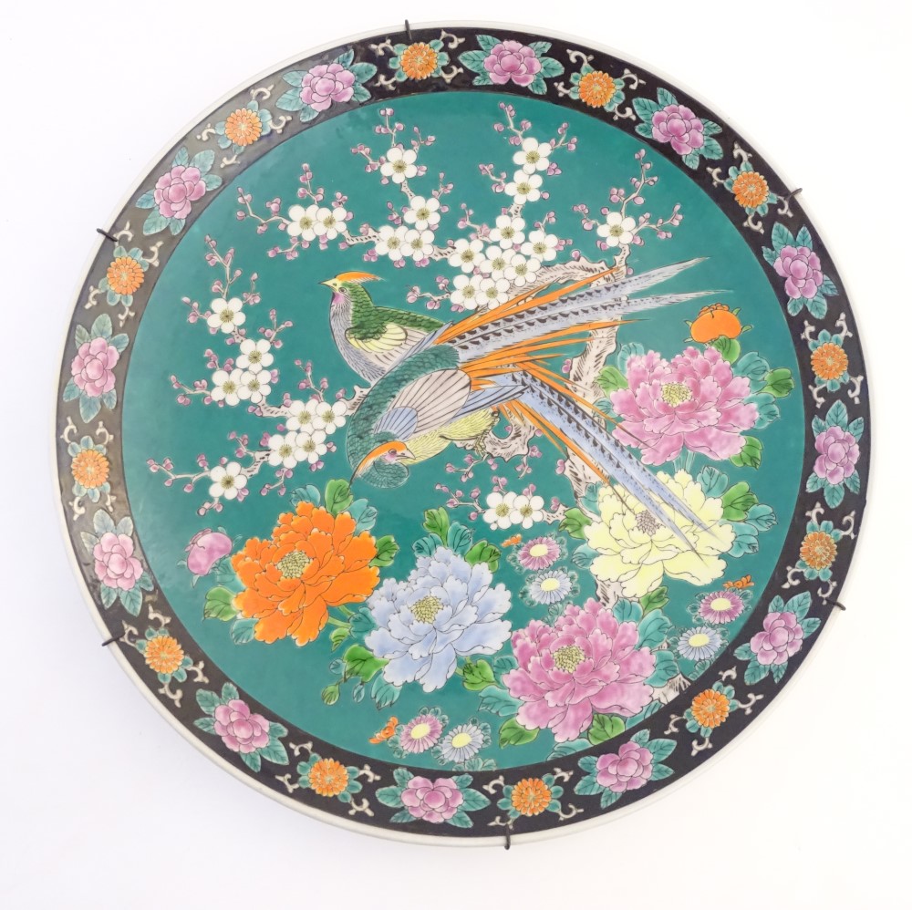 A Japanese charger depicting stylised pheasants, peonies, and cherry blossom on a green ground.