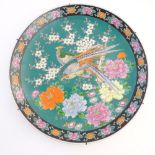 A Japanese charger depicting stylised pheasants, peonies, and cherry blossom on a green ground.