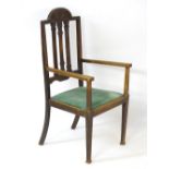 An early 20thC oak open armchair with an Art Nouveau inspired arched cresting rail,