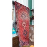 A large Eastern handmade woollen rug with red ground and blue,