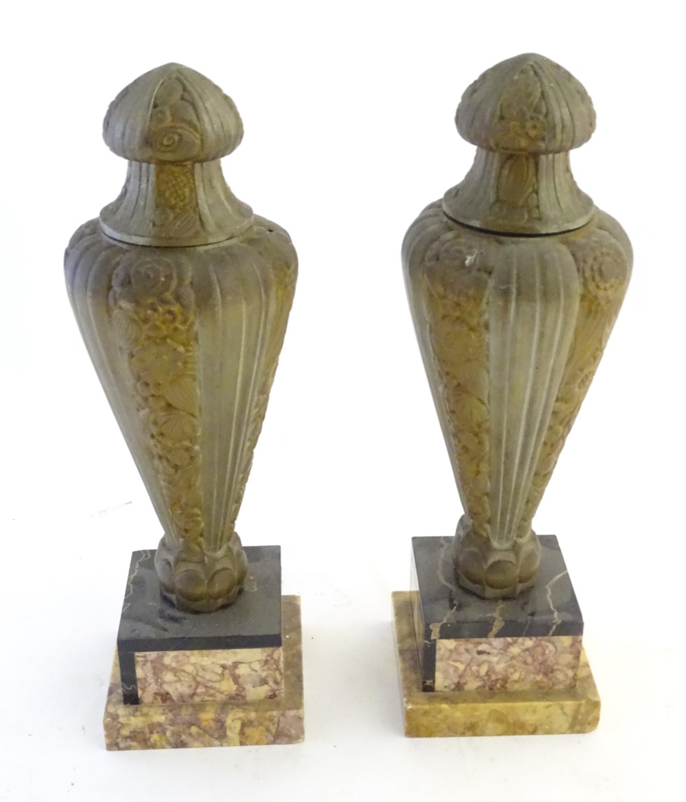 A pair of Art Deco gilded metal and marble lidded urn garnitures on square stepped bases,