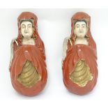 A pair of ceramic wall pockets formed as Oriental figures in red robes with gilt highlights.