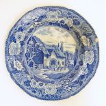 A 19thC blue and white transferware plate depicting a country scene with a thatched cottage,