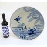 An oriental blue and white charger with hand painted decoration of birds in a landscape. Approx.
