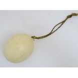 Ostrich Egg: a blown egg with twisted silk rope lanyard, 5 1/2" long.