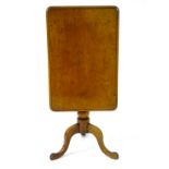 An early 19thC mahogany tilt top table with a rectangular top above a turned tapering stem and