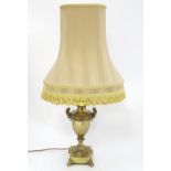 A 1970's mid-century modern urn shaped brass lamp with laurel decoration on a squared plinth,