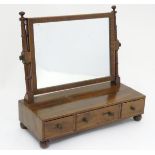 A Victorian mahogany toilet mirror with turned supports above three small drawers and raised on bun