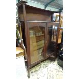 Arts & Crafts - A late 19thC / early 20thC walnut glazed cabinet with gallery above and raised on