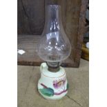 A small glass oil lamp with floral decoration, loop handle and clear glass chimney.