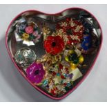 A heart shaped tin containing an assortment of brooches CONDITION: Please Note - we