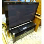 A Panasonic TV / television and stand with a glass top, together with a sky box etc.