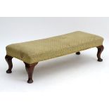 An early 20thC mahogany footstool with upholstered seat and cabriole legs.