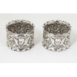 A pair of silver napkin rings with winged cherub detail.