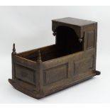 An 18thC oak crib with an overhanging hood and decorative hanging finials,