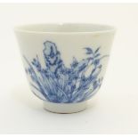 A small Chinese blue and white cup decorated with flowers and Chinese script. Character marks under.