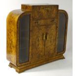 1950's Art Deco: a figured Walnut drinks cabinet of sapped form with glazed panel doors to side