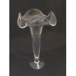 Glass vase: a tall 20thC lily, pedestal vase of clear glass with a wavy edged top and a clear foot,