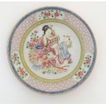 A Chinese famille rose plate decorated with three figures in an interior,