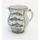 A Laurence McGowan British studio pottery jug, with green hand painted fish decoration.