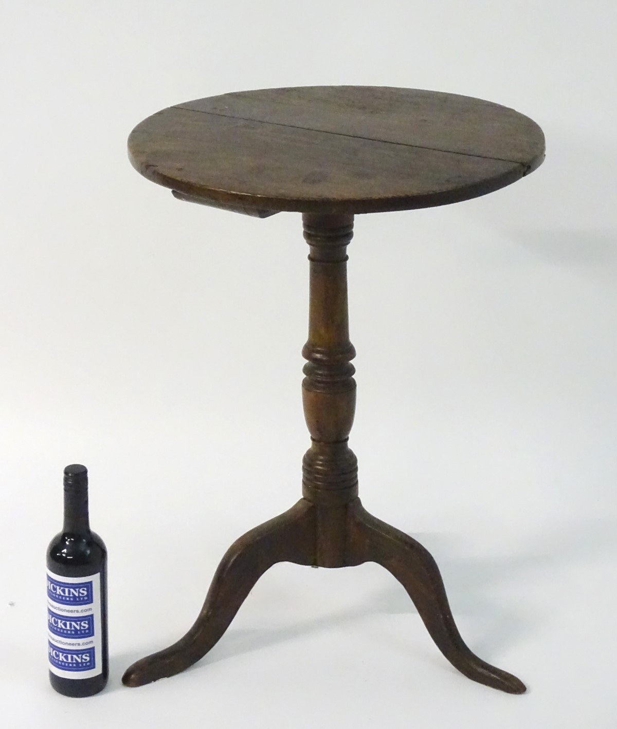 A late 18thC oak tripod table with a circular table top above a turned stem and standing on three