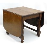 An early 20thC oak extending dining table, with drop flaps and two additional leaves,