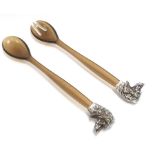 A pair of salad servers, the celluloid handles surmounted by silver plate dog head decoration.