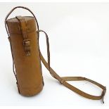 A lidded leather flask case of cylindrical form with a strap. The case 10” long x 3 1/2” diameter.
