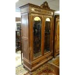 A late 19thC walnut armoire with a carved pediment above a moulded frieze and two large arched