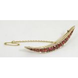 A 9ct gold crescent shaped brooch set with red stones. Chester c.1903.