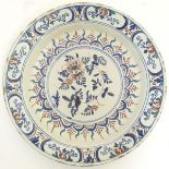 A Continental earthenware charger decorated with stylised flowers and scrolling foliage.