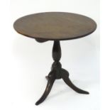 An early 19thC oak topped tripod table with a circular tilt top above a turned stem with three